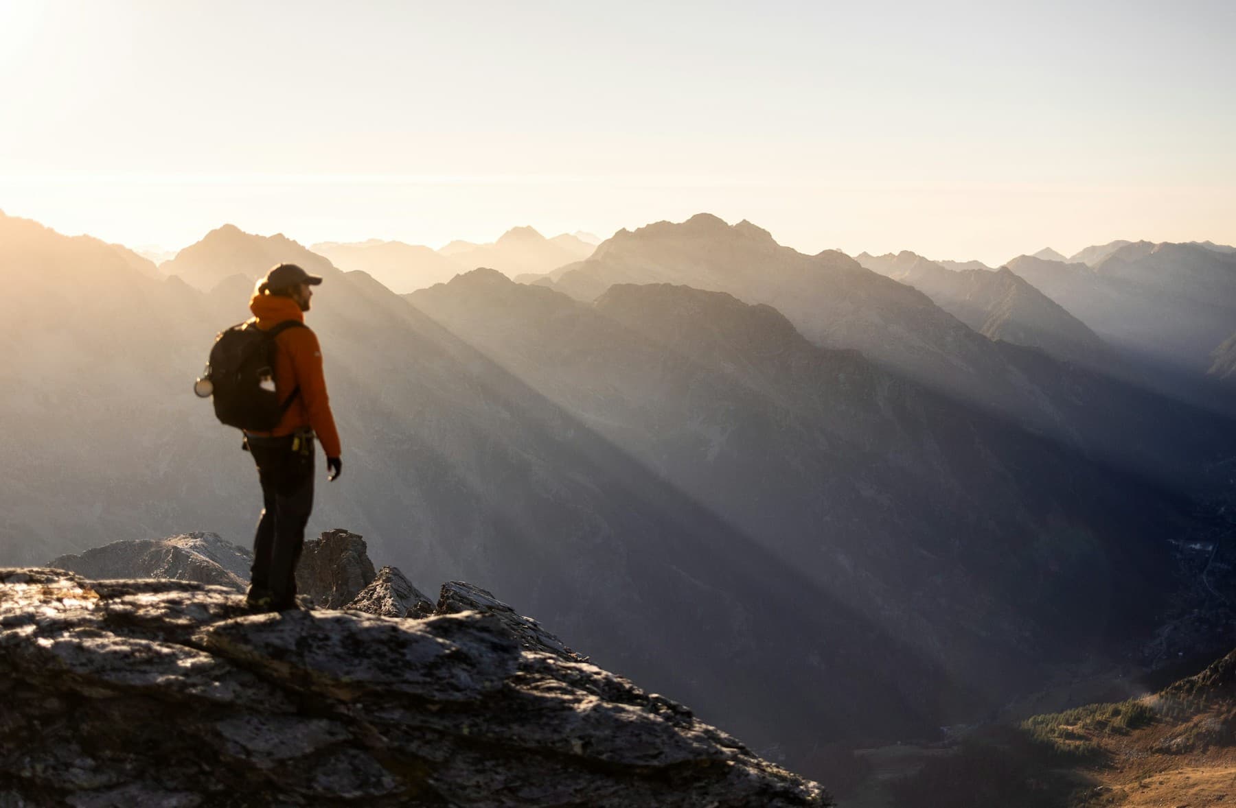 Hiker facing a mountain horizon at sunrise